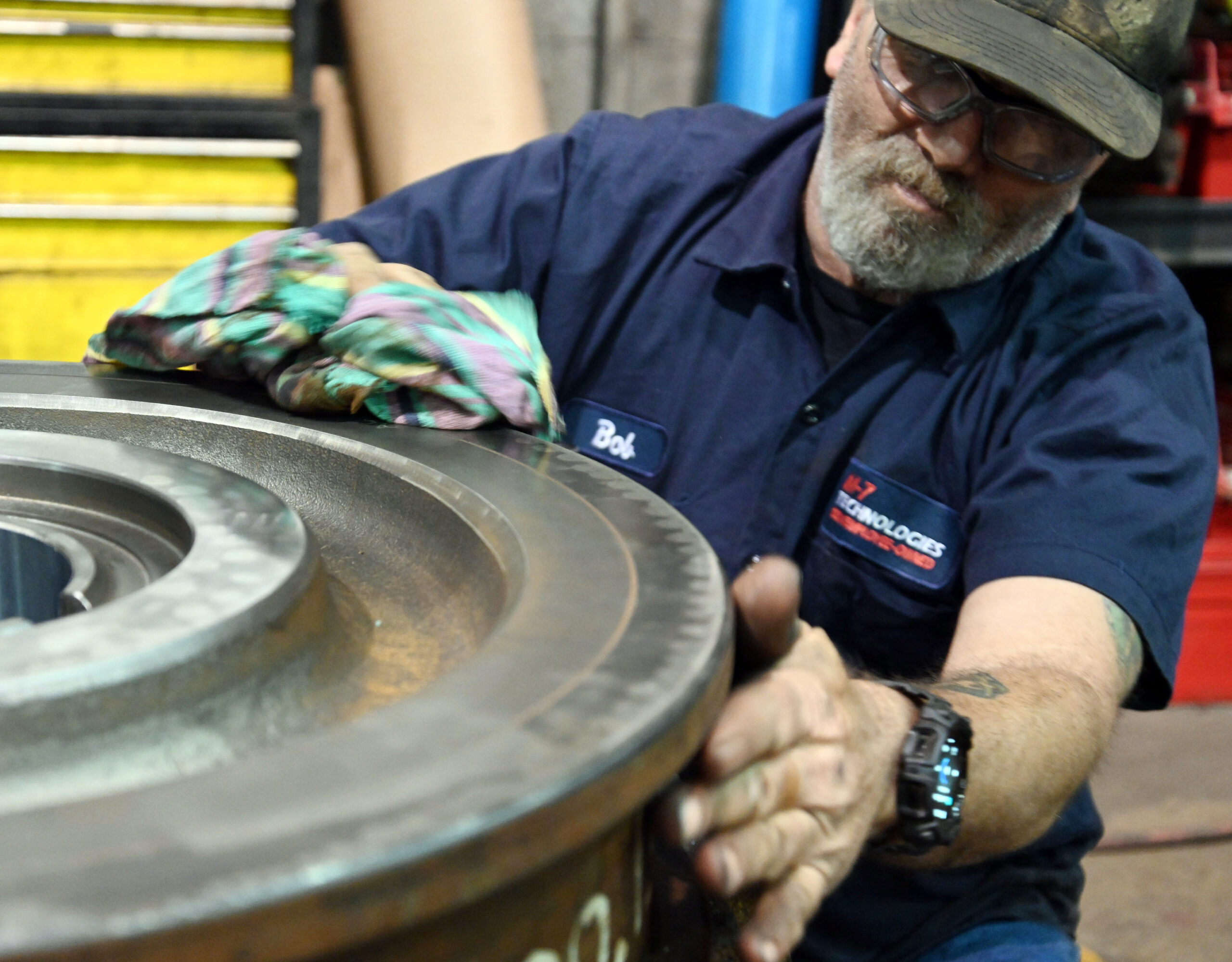 M-7 Technologies technician cleaning a round metal piece with a cloth