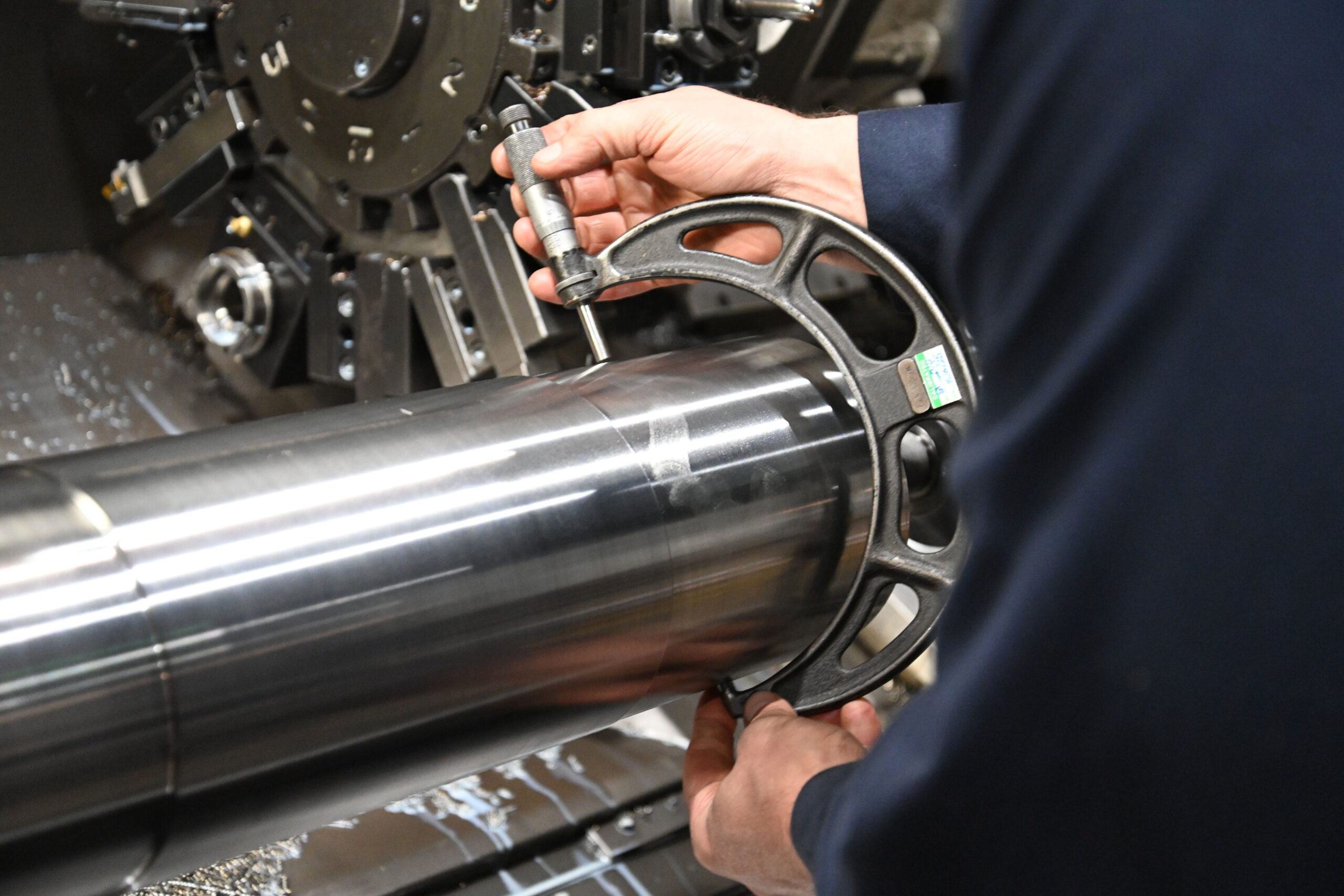 M-7 Technician measuring a metal tube preparing it for the next step in the refurbishing process